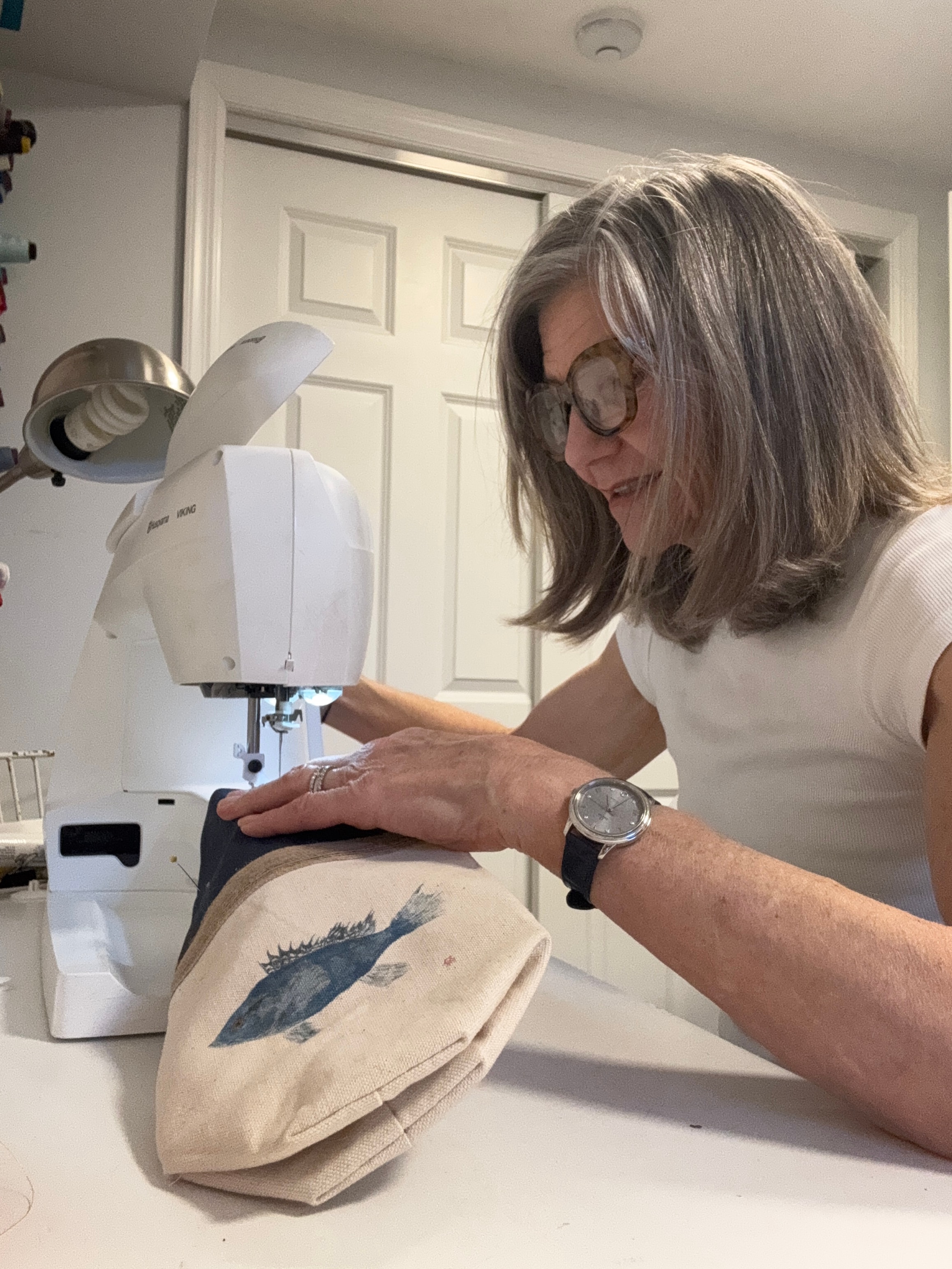 Bridget sewing a canvas tote bag with a fish print